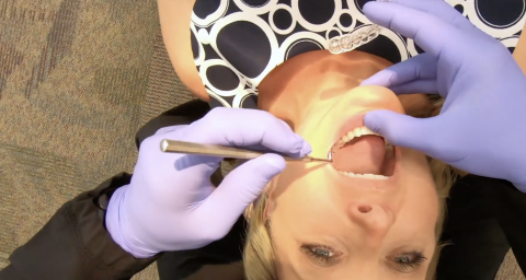 A woman is getting her teeth checked by an orthodontist