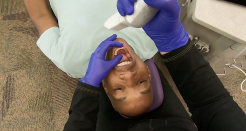 A young man is getting her teeth checked by an orthodontist